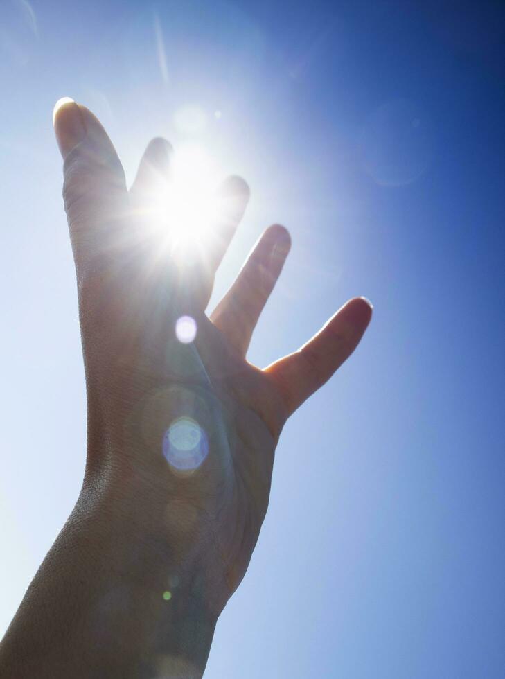 fêmea mãos dentro a azul céu dentro a luz de fundo foto