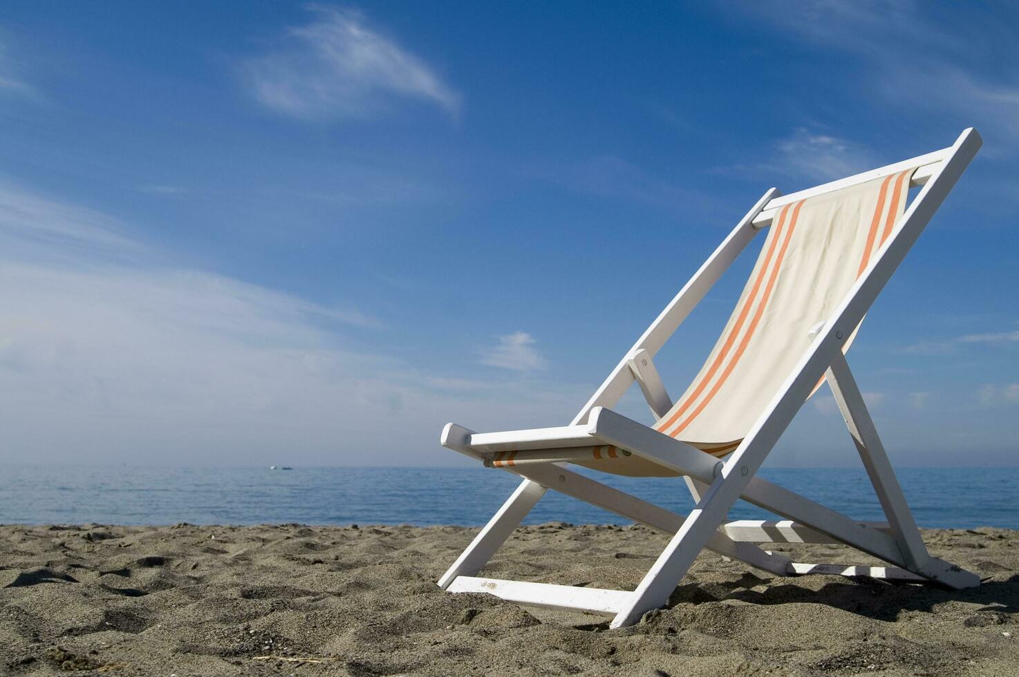 uma de praia cadeira em a areia com uma azul céu foto
