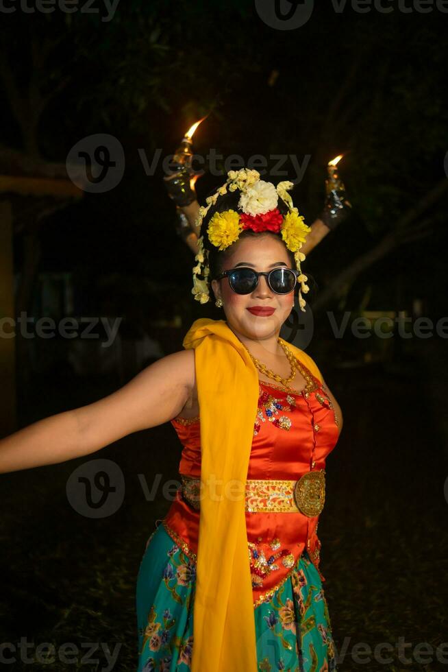 uma tradicional javanese dançarino carrinhos e danças com uma flexível corpo enquanto vestindo oculos de sol foto