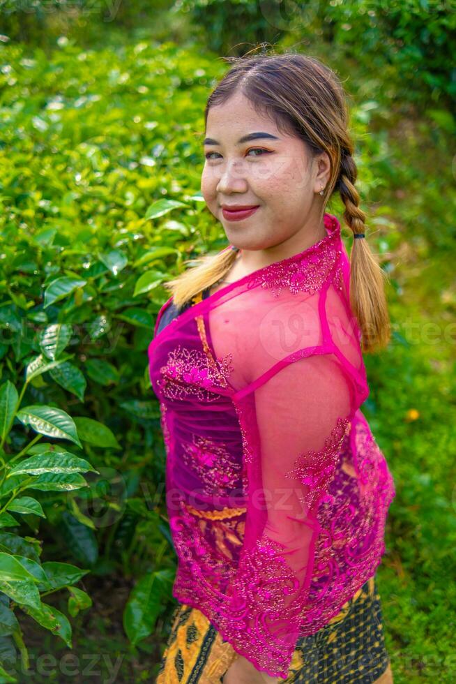 a ásia mulher dentro uma Rosa traje é posando dentro frente do uma chá plantação foto