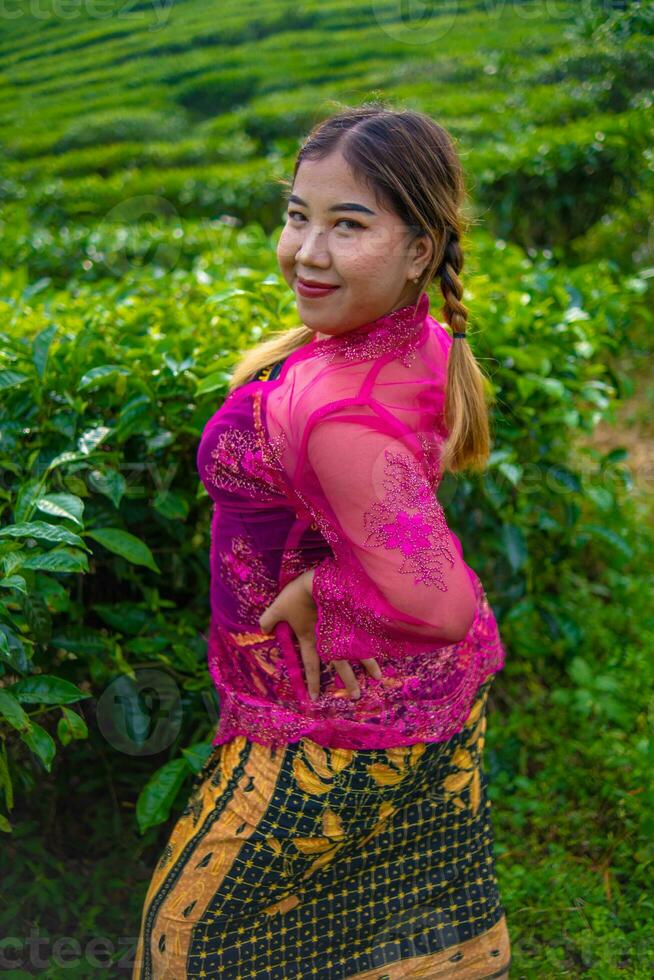 a ásia mulher dentro uma Rosa traje é posando dentro frente do uma chá plantação foto