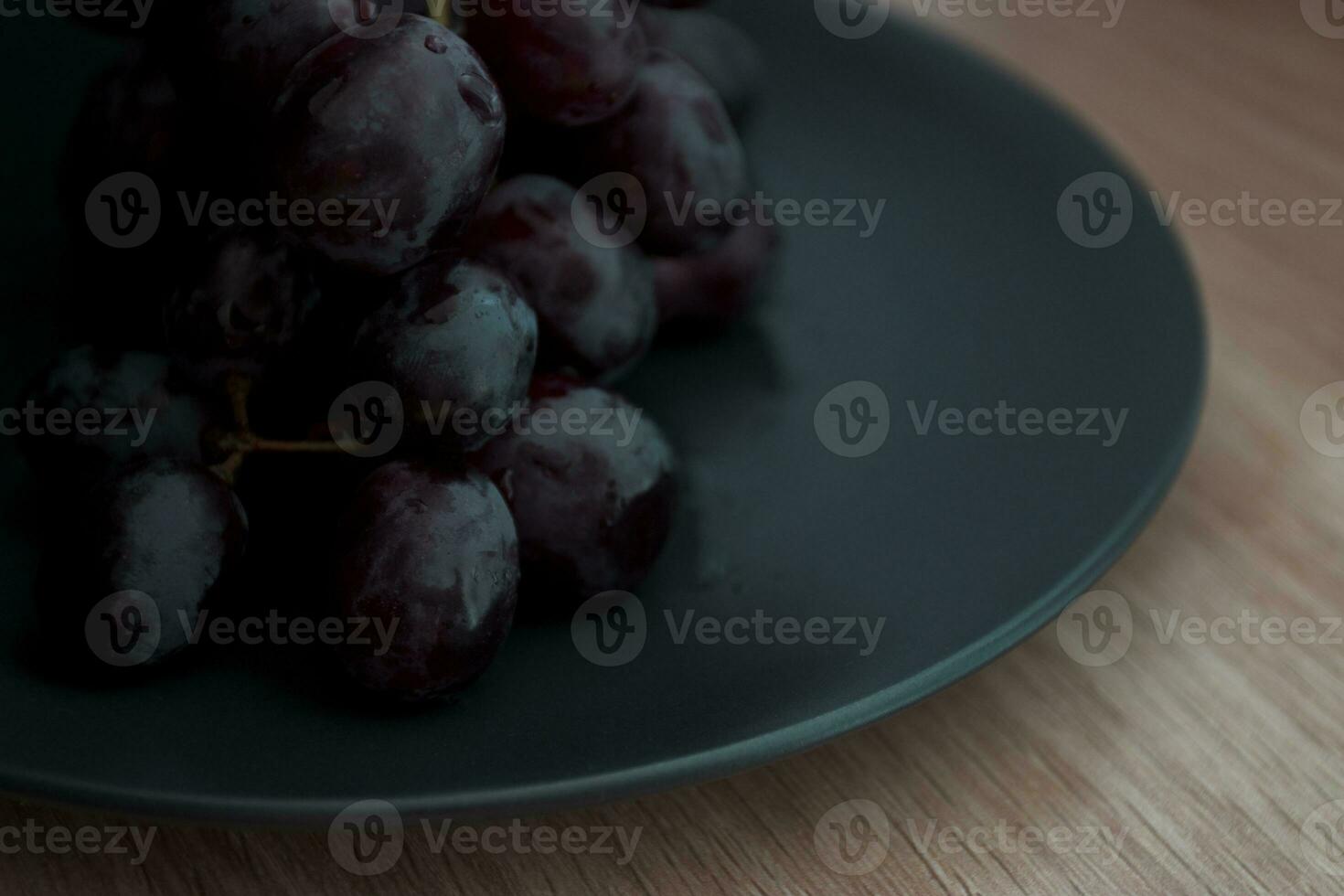 fechar-se do uvas com água gotas em uma Preto cerâmico placa. foto