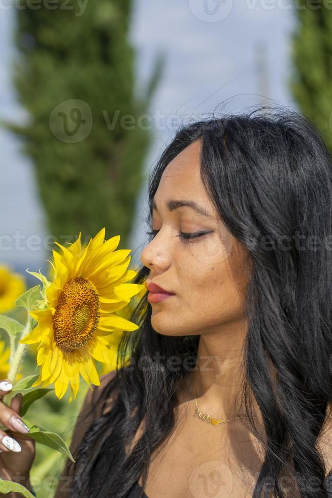 garota indiana cheirando uma flor de girassol foto