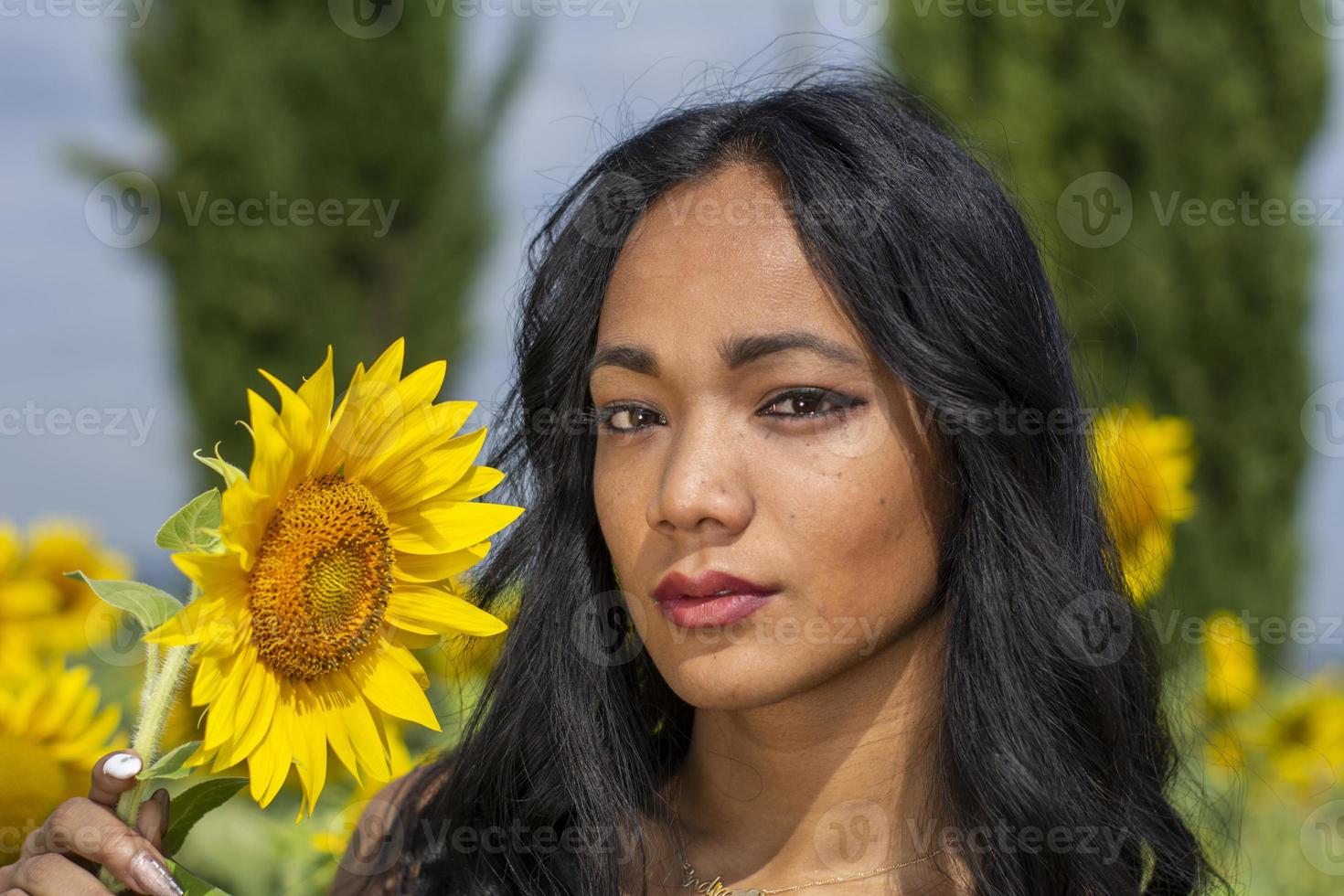 garota indiana cheirando uma flor de girassol foto