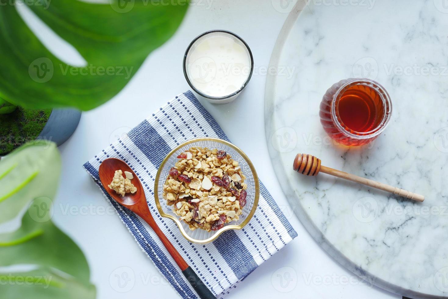 cereal matinal na tigela, pão e mel no fundo branco foto