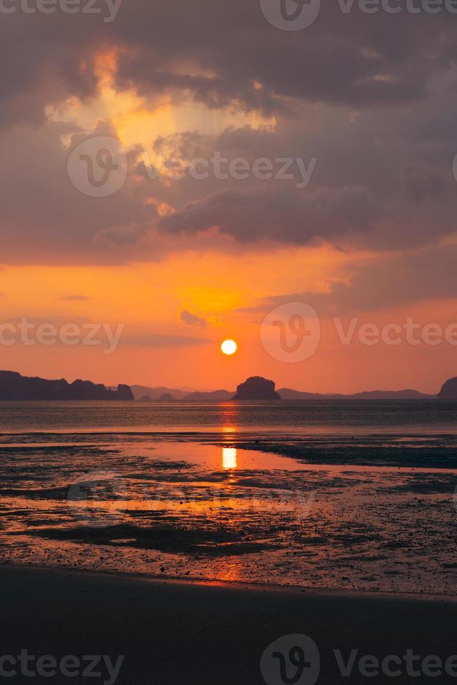 lindo pôr do sol na praia no verão com reflexo do sol na água foto