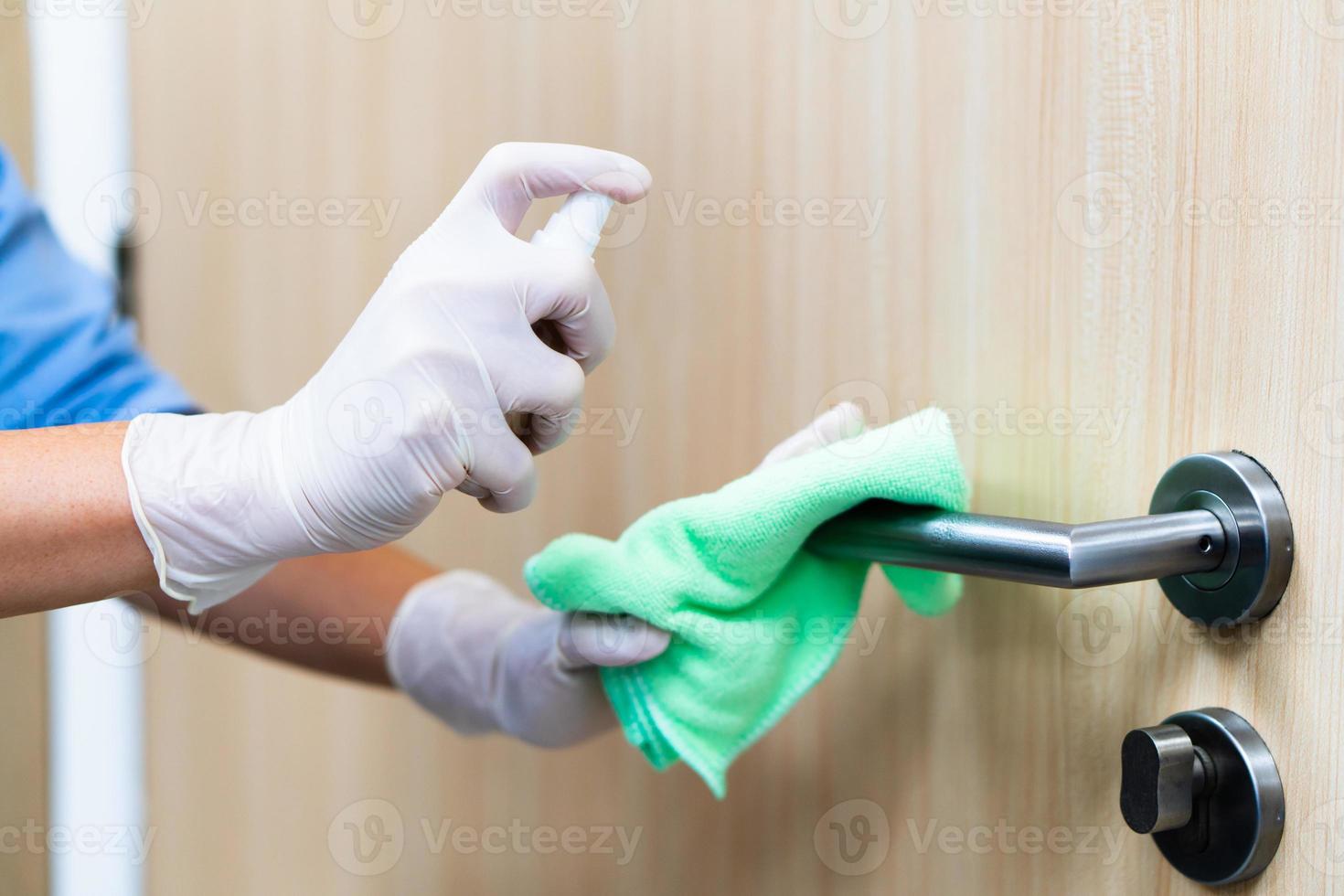 mulher desinfetando uma maçaneta de porta foto