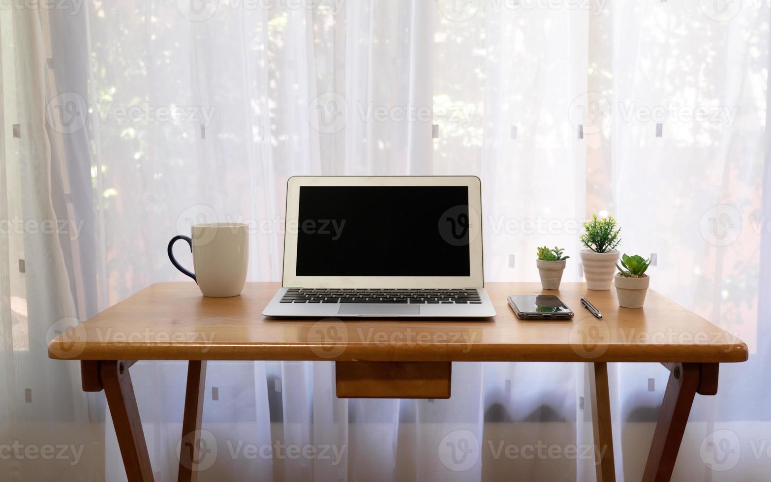 mesa de trabalho, incluindo computador, caneca de café, telefone inteligente na sala de estar foto