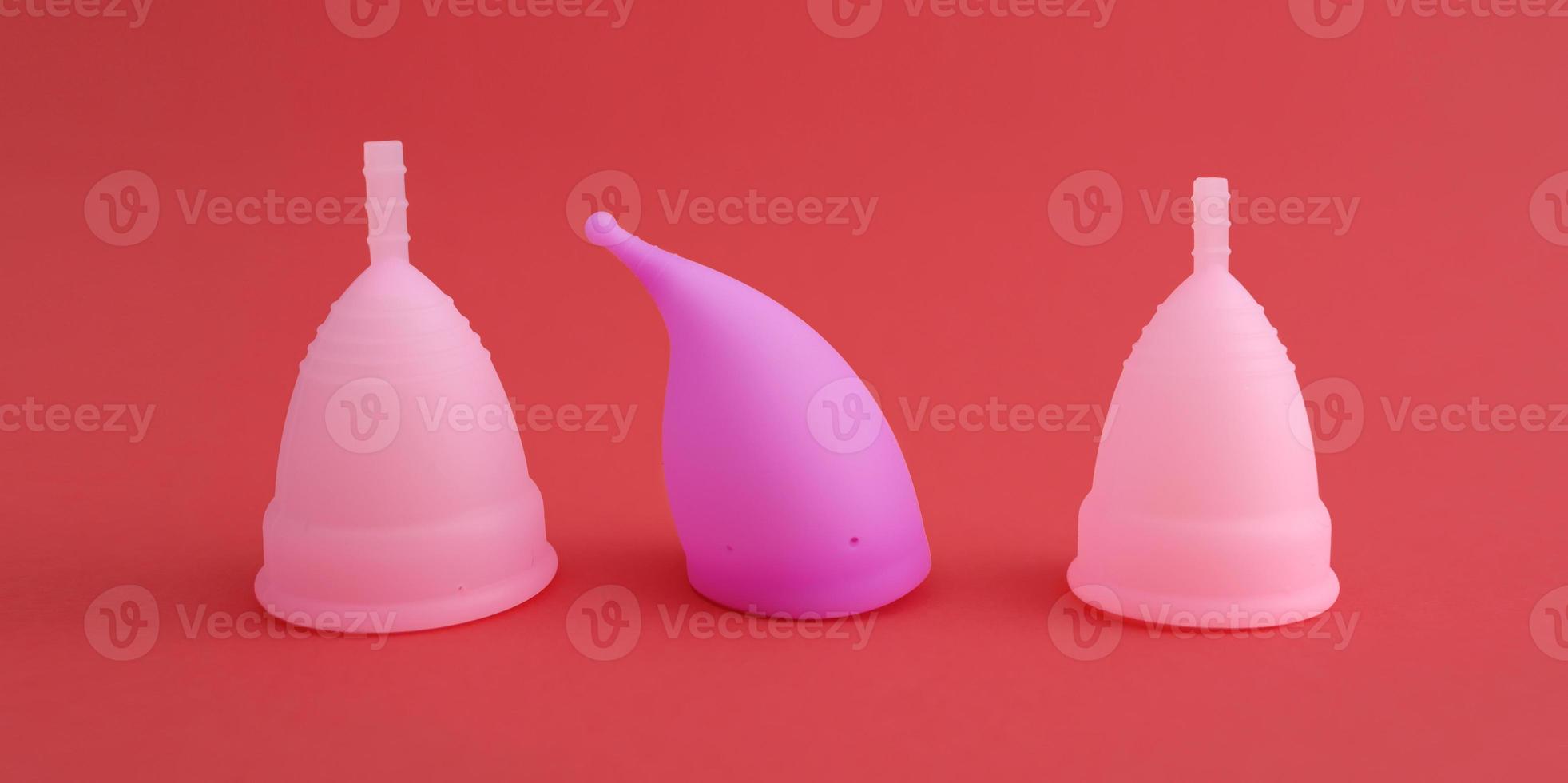três copos menstruais de silicone reutilizáveis rosa diferentes foto