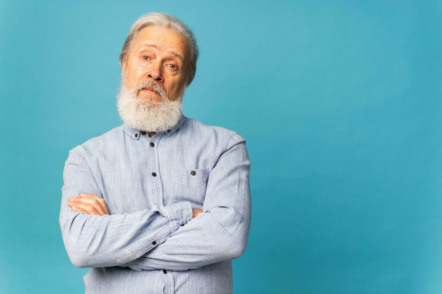 retrato do surpreso cinzento cabelo barba avô velho homem sobre azul cor fundo com cópia de espaço foto