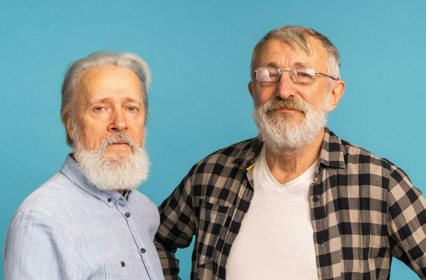 retrato dois idosos homem amigos em pé sobre azul fundo - amizade, envelhecido e Senior pessoas foto