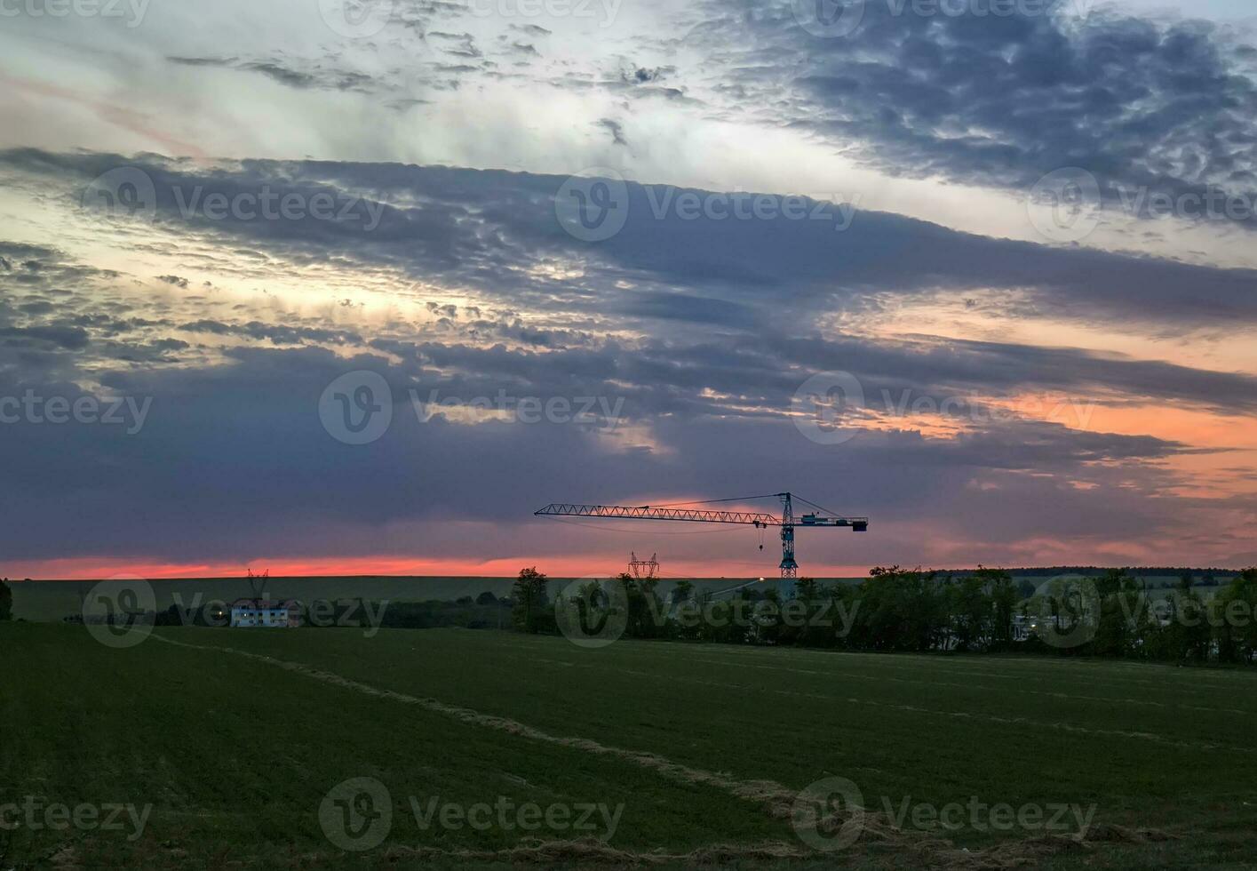 panorama com construção e silhueta do a guindaste dentro a campo. foto