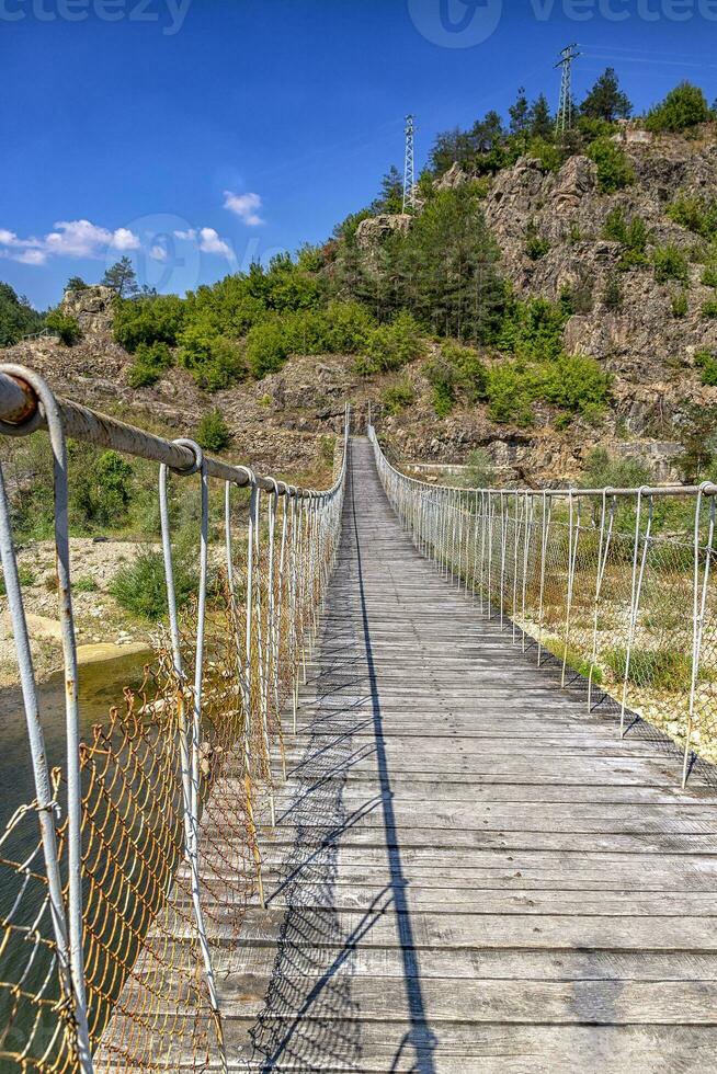 de madeira corda suspensão ponte para andar cruzando rio dentro a montanha foto