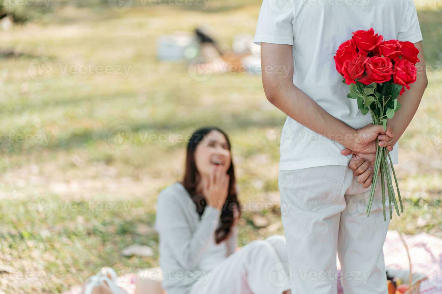 feliz romântico casal dentro dia dos namorados dia ásia homem se escondendo vermelho rosa flor atrás para surpresa dele namorada. foto