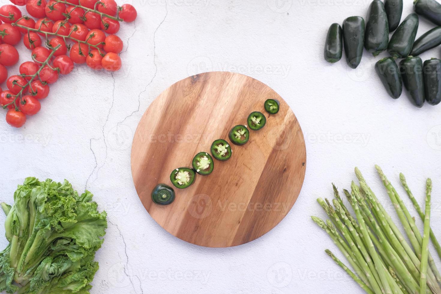 pimenta jalapeño, aspargos, tomate cereja, alface na tábua de cortar foto