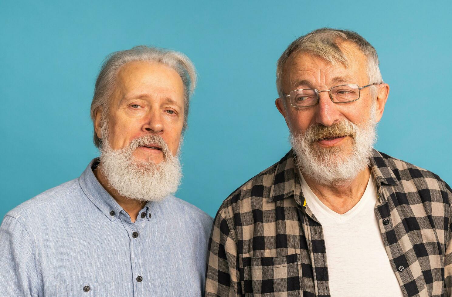 retrato dois idosos homem amigos em pé sobre azul fundo - amizade, envelhecido e Senior pessoas foto