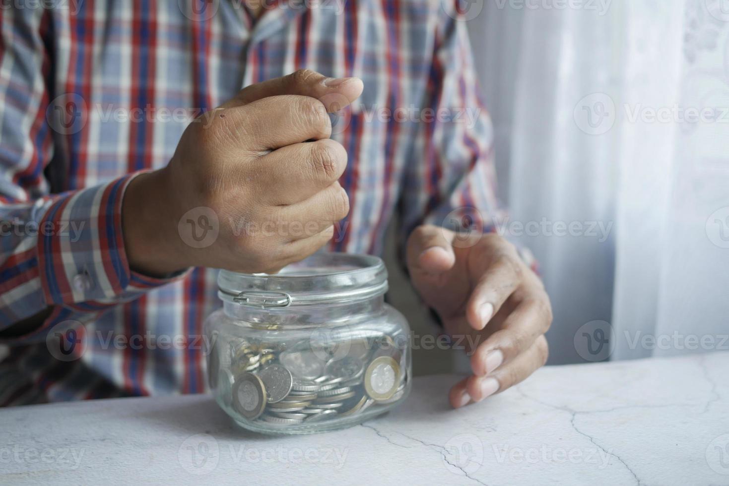 jovem guardando moedas em uma jarra branca localizada foto