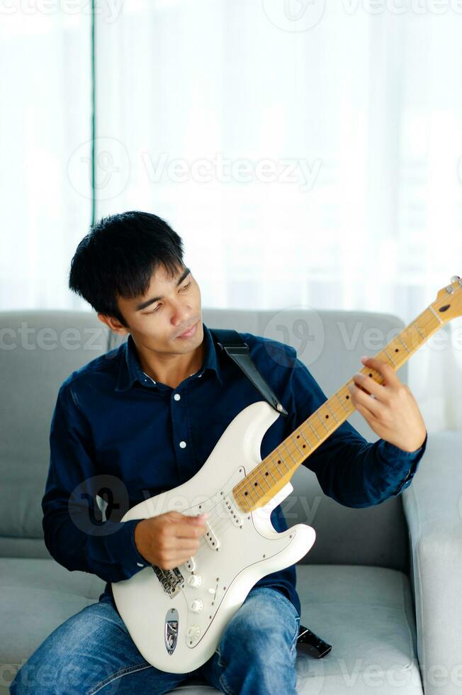 guitarrista jogando guitarra em sofá às casa praticando guitarra às casa relaxar de jogando amarrado instrumentos. foto