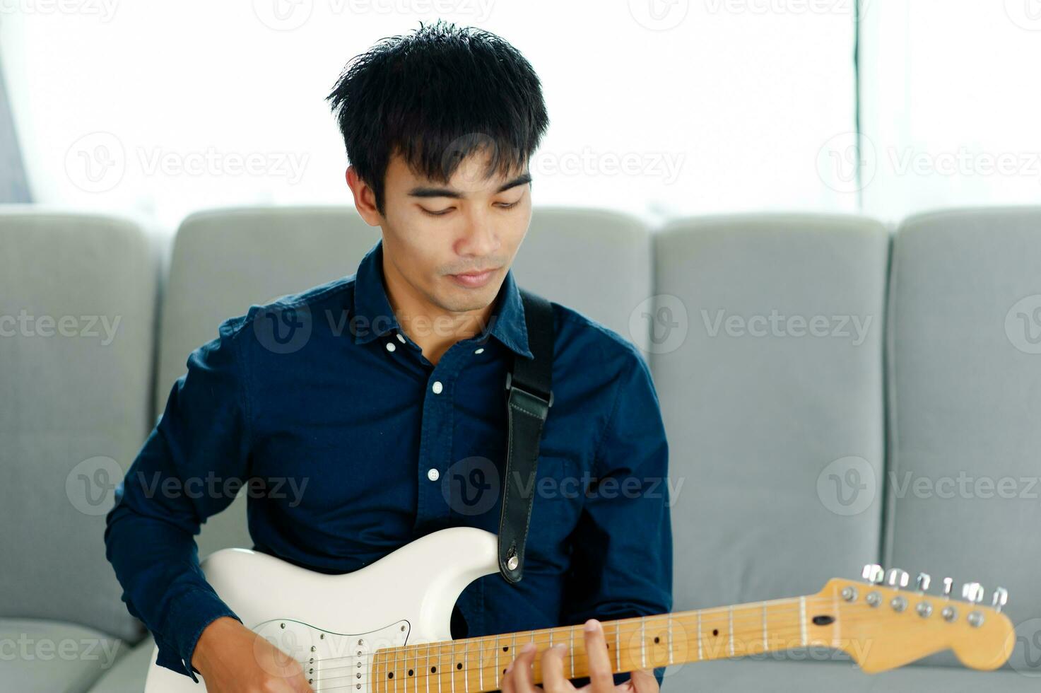 guitarrista jogando guitarra em sofá às casa praticando guitarra às casa relaxar de jogando amarrado instrumentos. foto