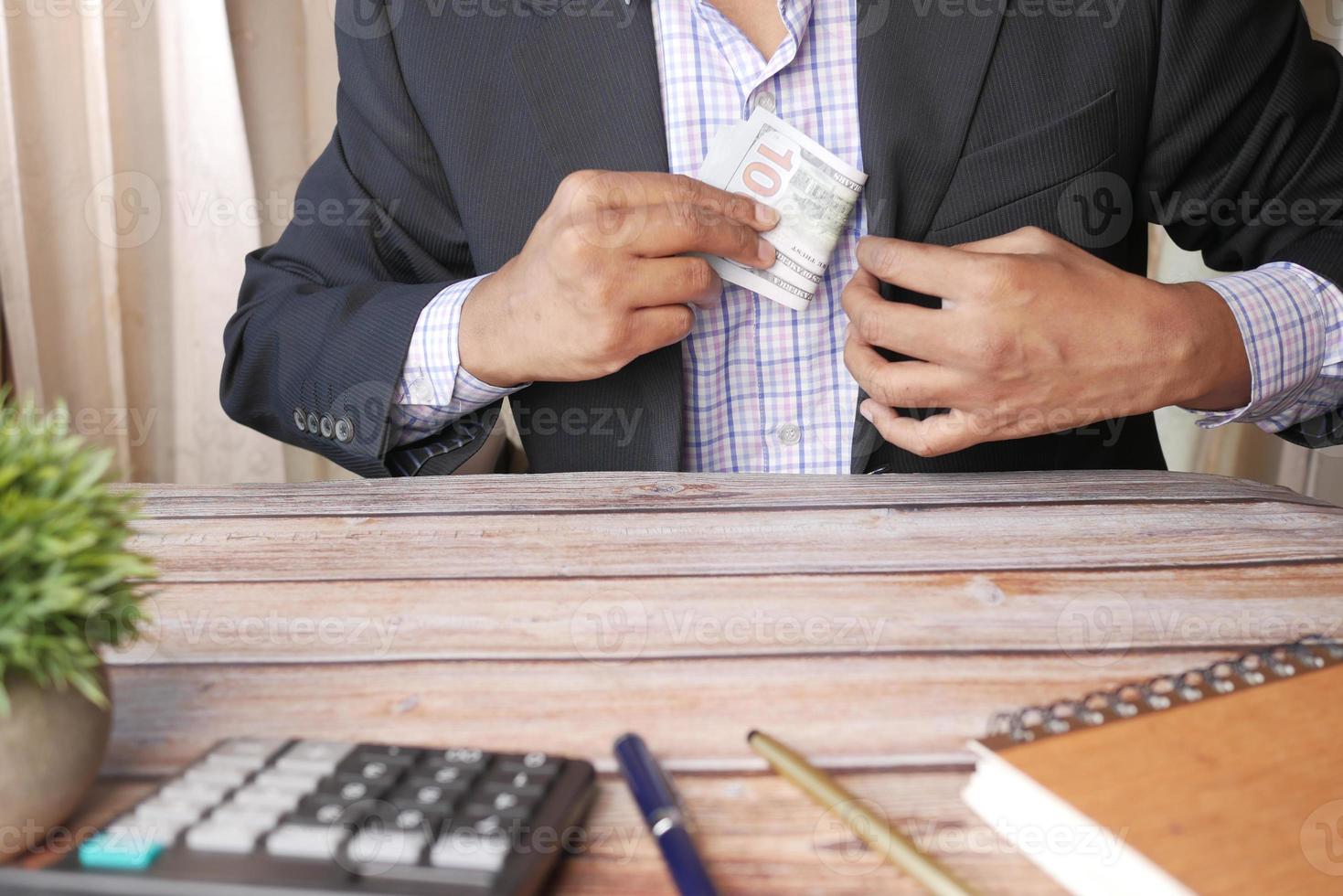 jovem empresário oferecendo dinheiro enquanto está sentado na mesa foto