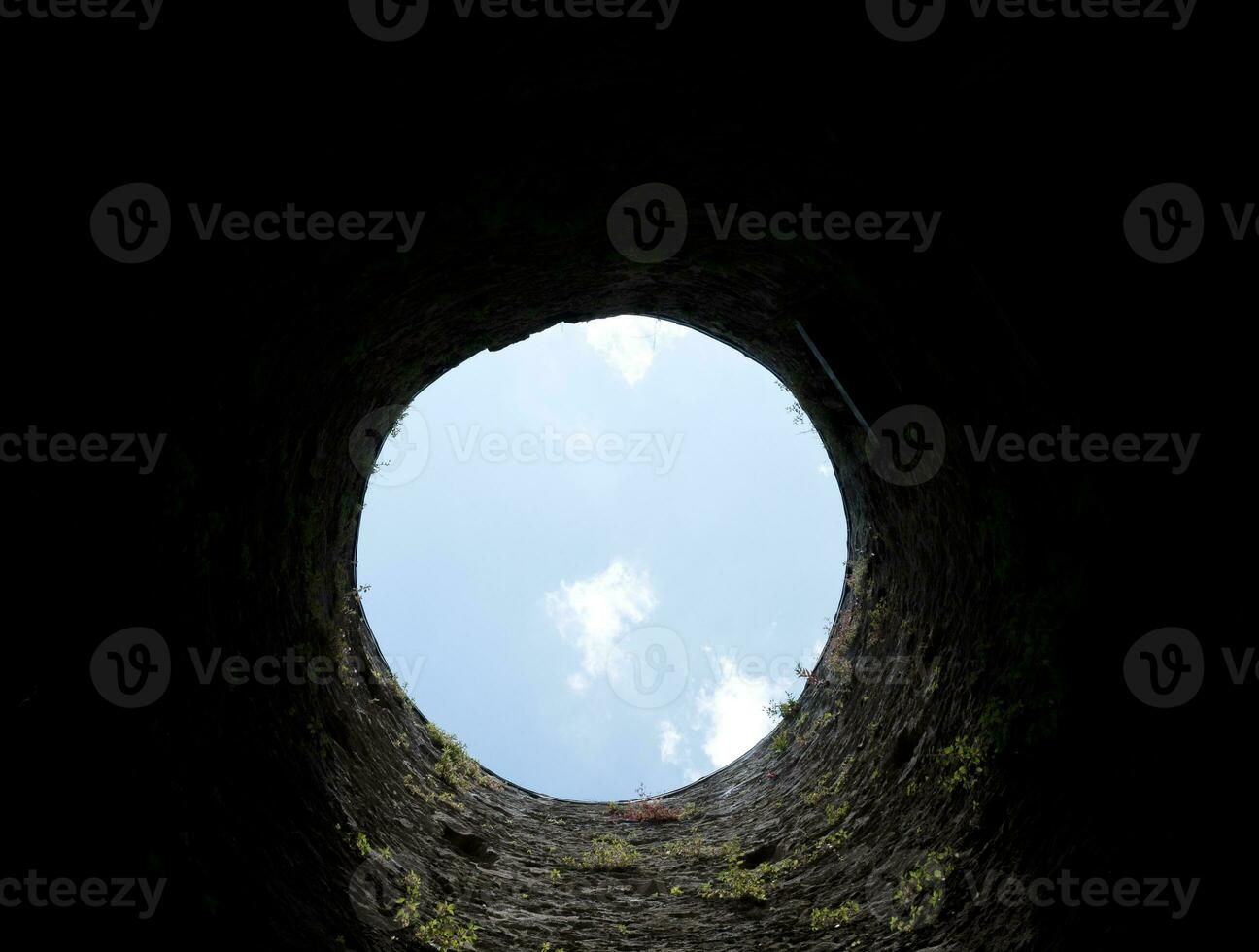 pedra bem buraco, velho construção a partir de dentro, tijolo paredes e azul céu fundo, outono baixa dentro a bem conceito foto