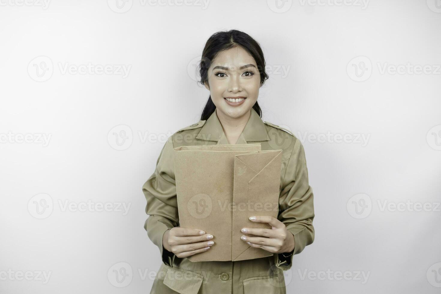 um jovem e belo trabalhador asiático com uniforme marrom trazendo documento. pns indonésio. foto