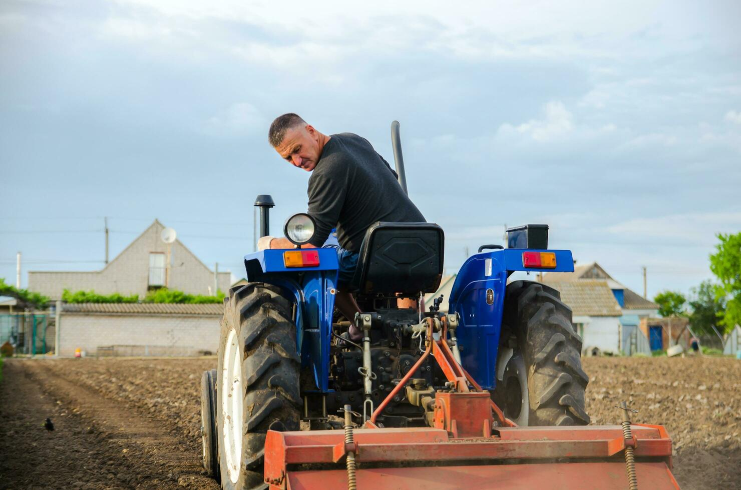 kherson oblast, Ucrânia - pode 29, 2021 uma agricultor em uma trator limpa a campo depois de colheita. preparação do terra para futuro plantio Novo cortar. moagem solo, afrouxamento terra antes corte linhas foto