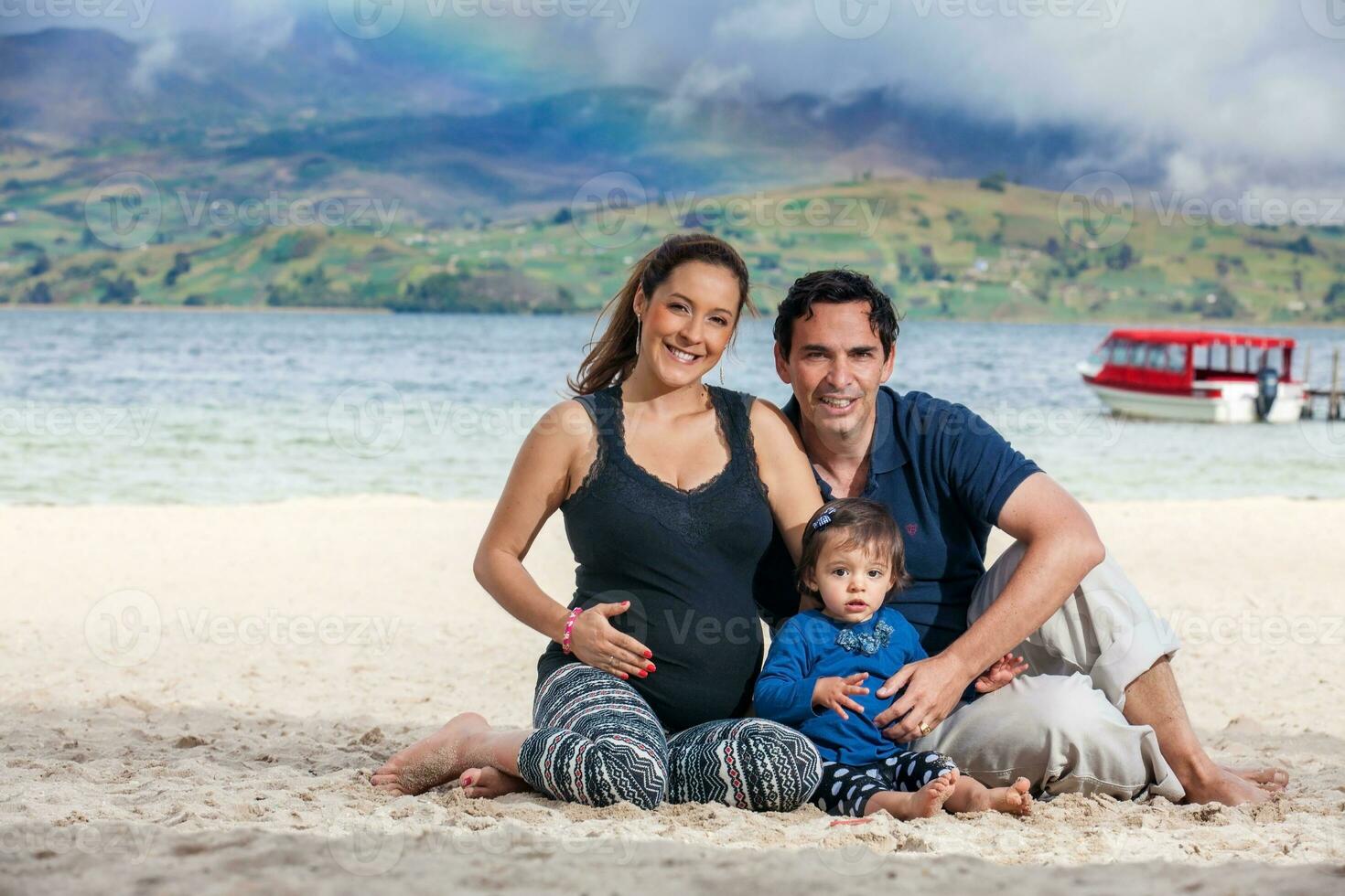 jovem casal esperando para seus segundo bebê tendo Diversão com seus bebê menina às a lindo branco de praia do lago total localizado dentro a departamento do boyaca às 3.015 metros acima mar nível dentro Colômbia foto