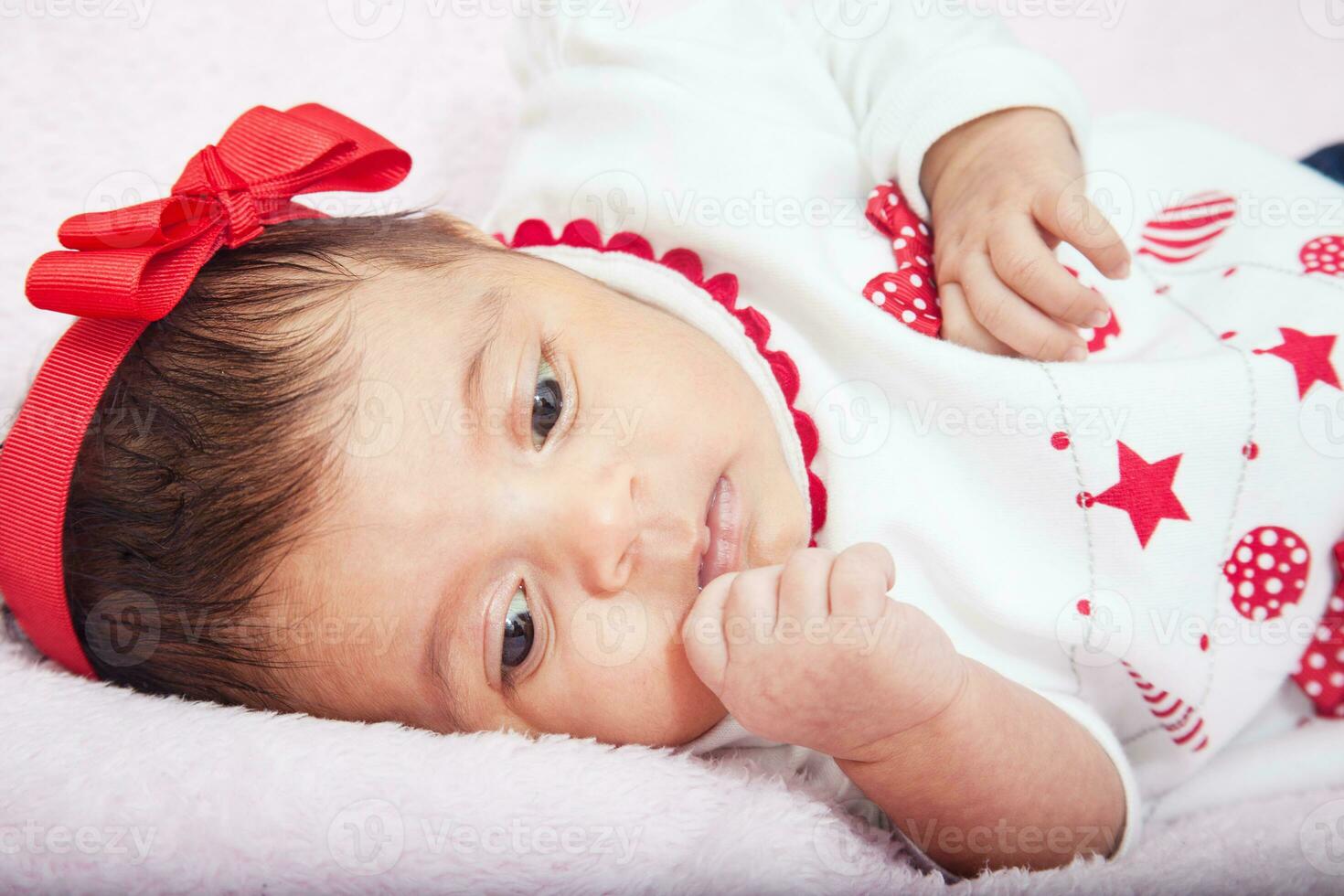 fechar acima do uma doce 1 mês bebê menina vestindo uma vermelho e branco Natal camiseta. foto