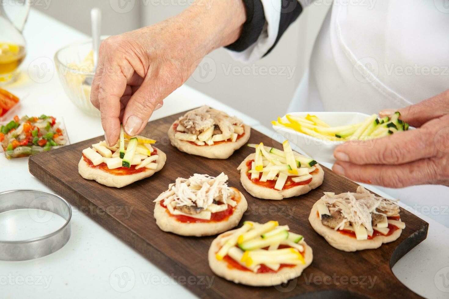 adicionando coberturas para a mini pizzas. adicionando legumes. delicioso caseiro mini pizzas preparação. foto