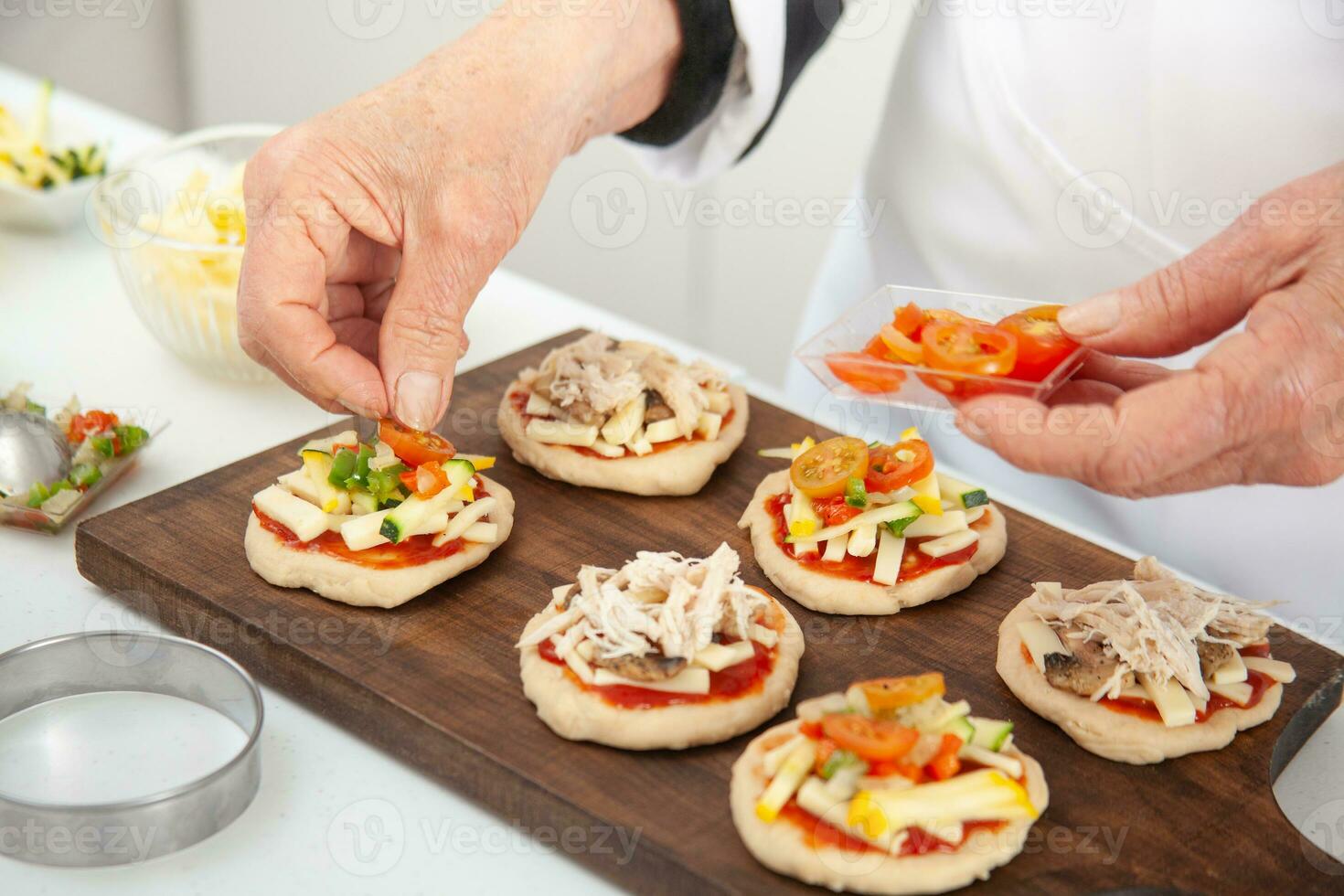 adicionando coberturas para a mini pizzas. delicioso caseiro mini pizzas preparação. foto