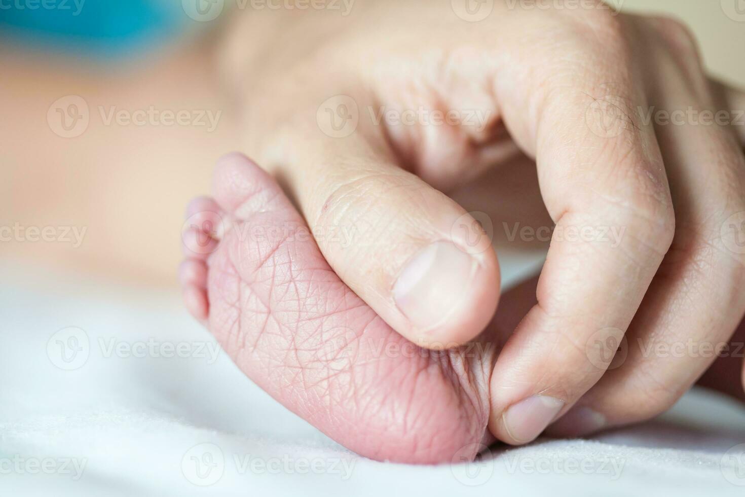 fechar-se do uma recém-nascido pé e dela pai mãos às hospital em a dia do dela nascimento foto