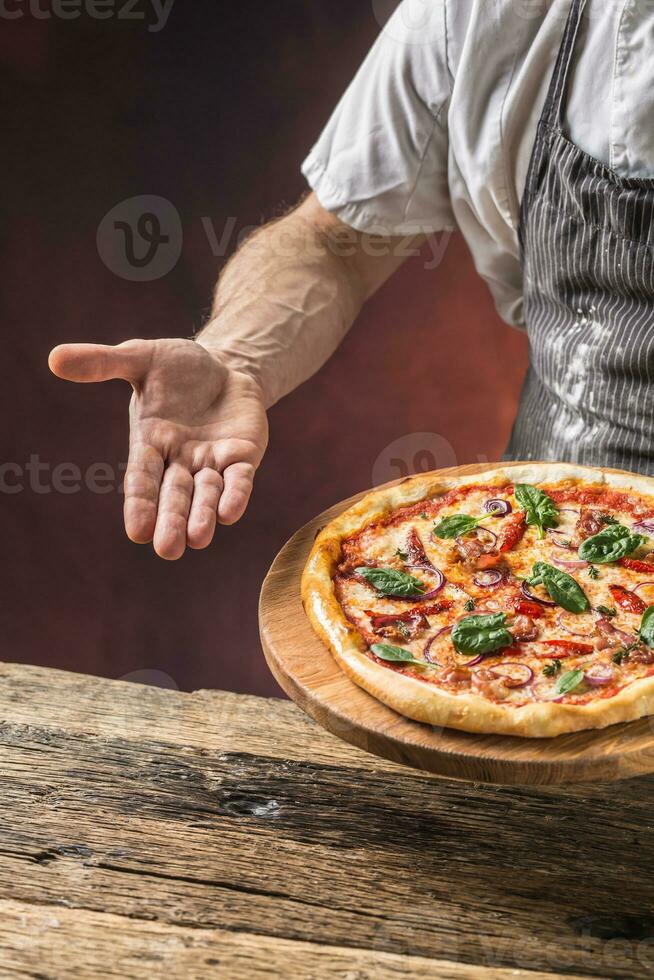 chefe de cozinha e pizza. chefe de cozinha oferta pizza dentro hotel ou restaurante foto