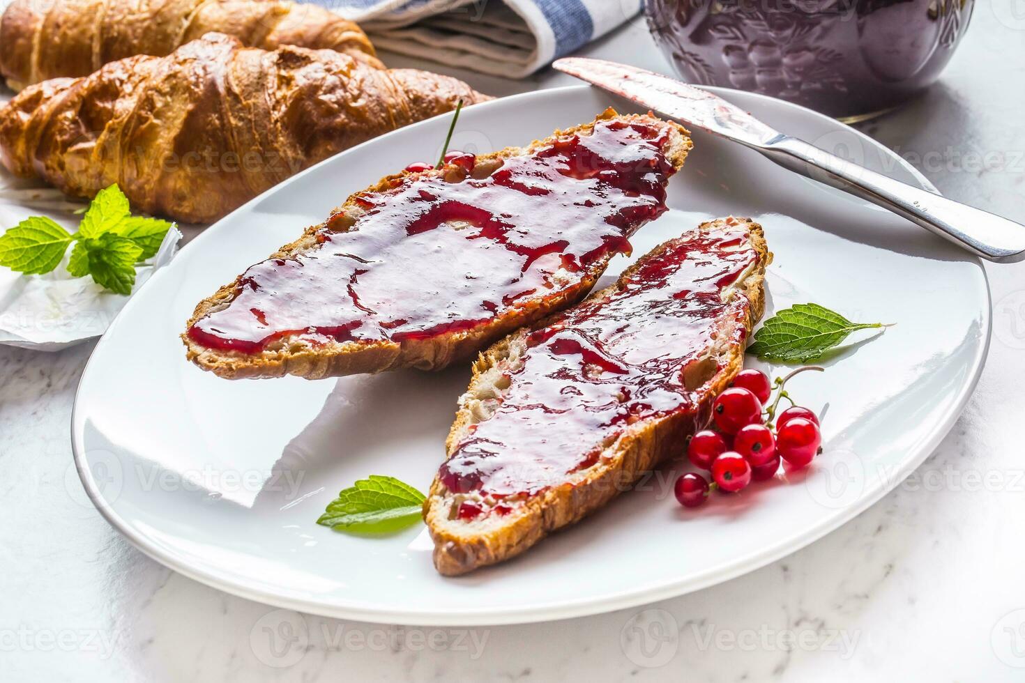 saboroso café da manhã com vermelho groselhas marmelada croissants manteiga e hortelã folhas foto