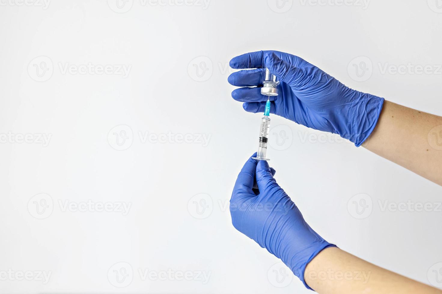 um trabalhador médico em luvas médicas aplica uma dose da vacina contra o coronavírus em uma seringa foto