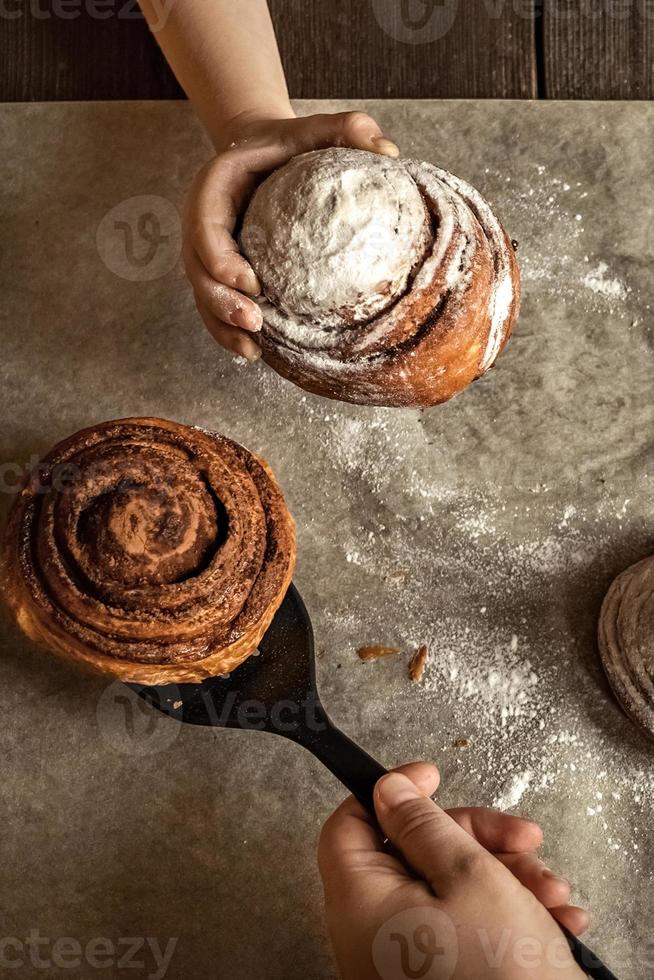 mão de criança pega um pão de canela recém-assado foto