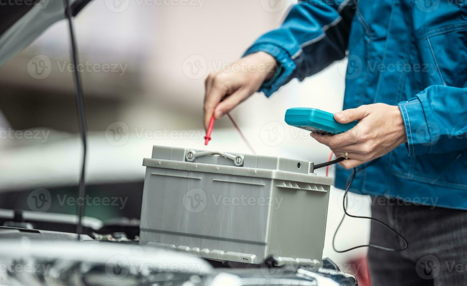 carro reembolsado garagem técnico Verificações vida útil do uma carro bateria com uma multímetro foto