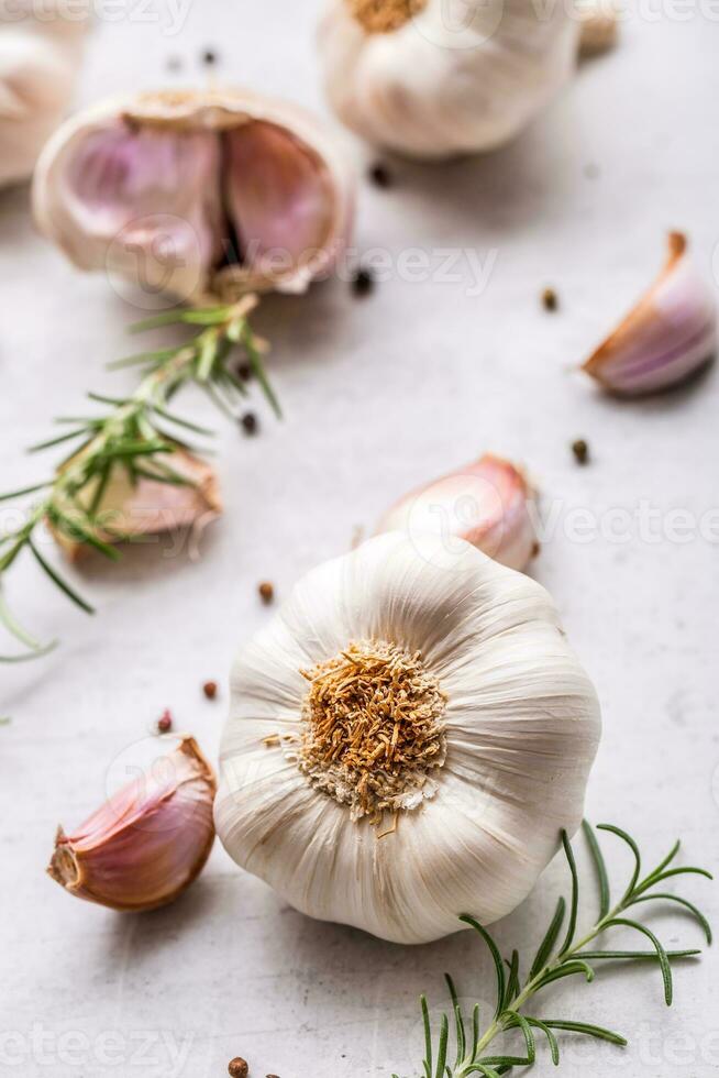 alho. alho lâmpadas. fresco alho com alecrim e Pimenta em branco concreto borda foto