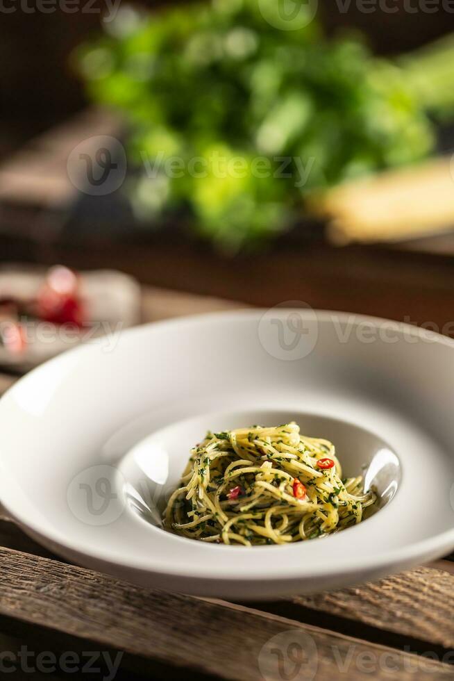 espaguete aglio e olio com Oliva óleo, gralico, manjericão,, tomates e Pimenta chili servido em uma profundo prato foto