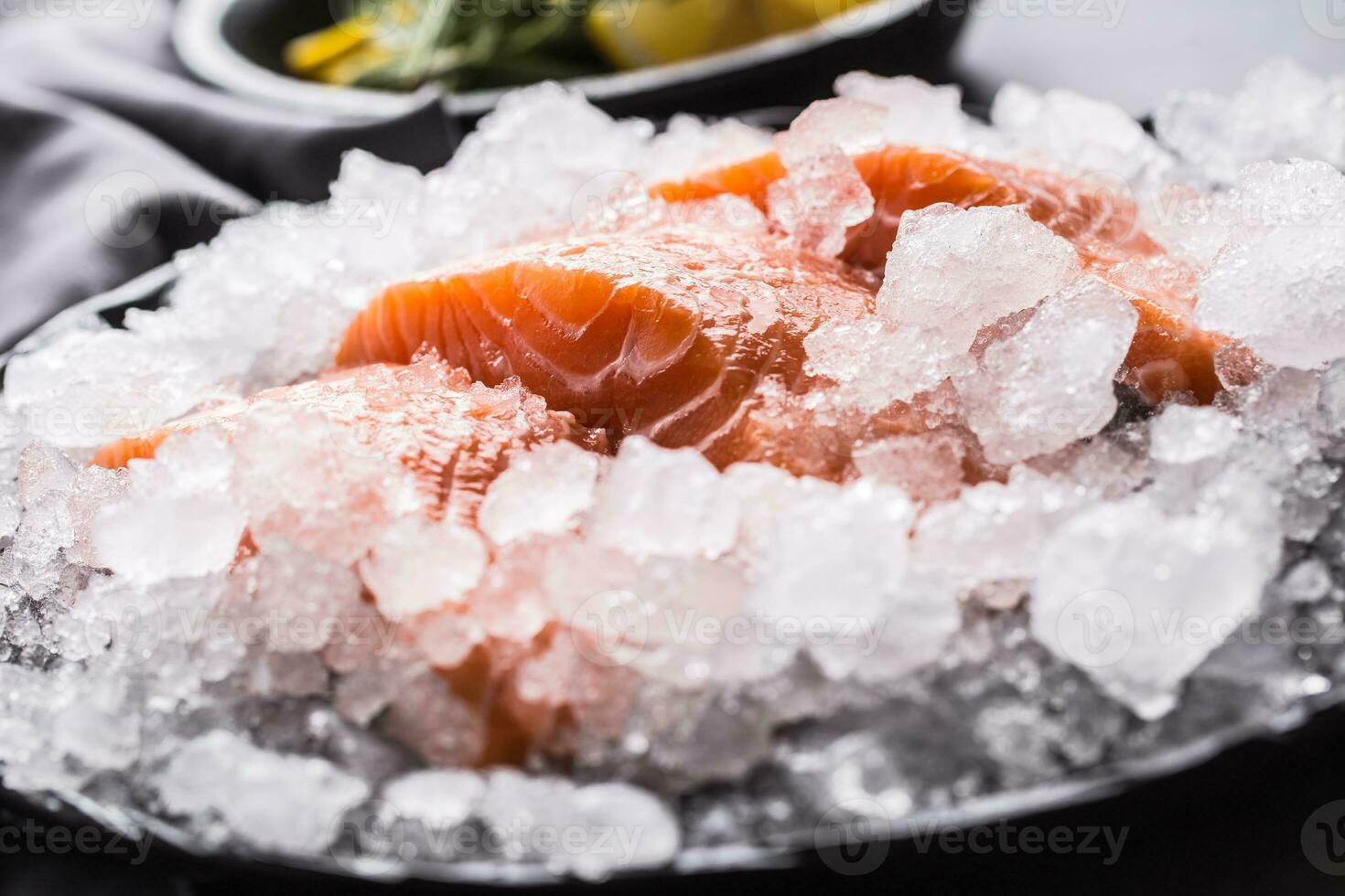 repartido cru salmão filetes dentro gelo em prato com limão e alecrim foto