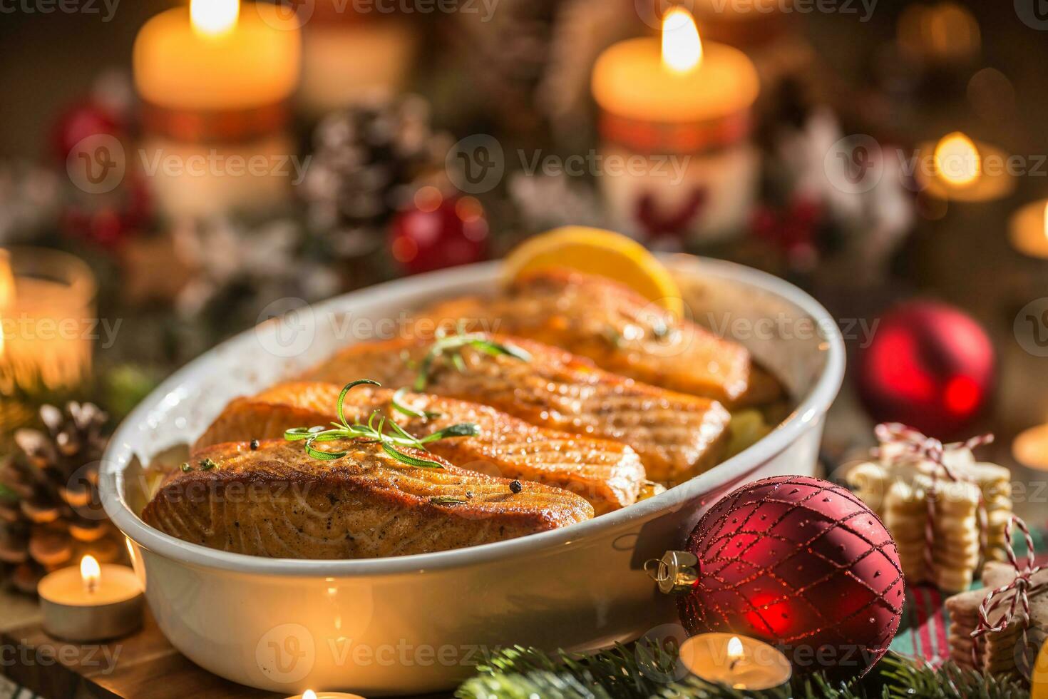 Natal jantar a partir de peixe salmão dentro assar prato com festivo decoração advento guirlanda e velas. foto