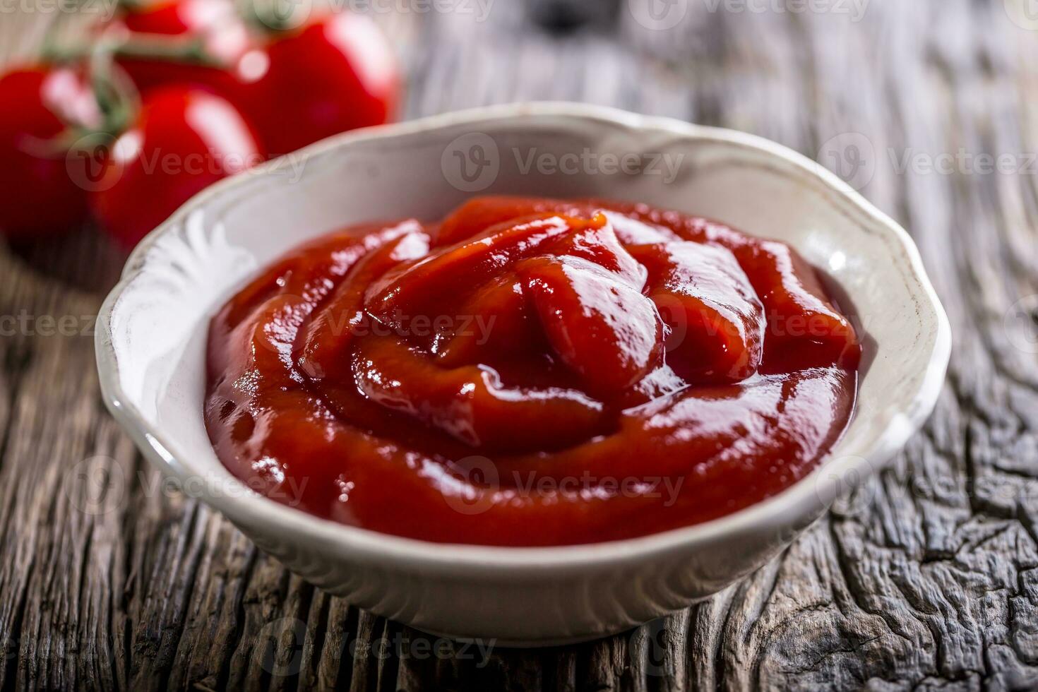 ketchup ou tomate molho dentro branco tigela e cereja tomates em de madeira mesa. foto