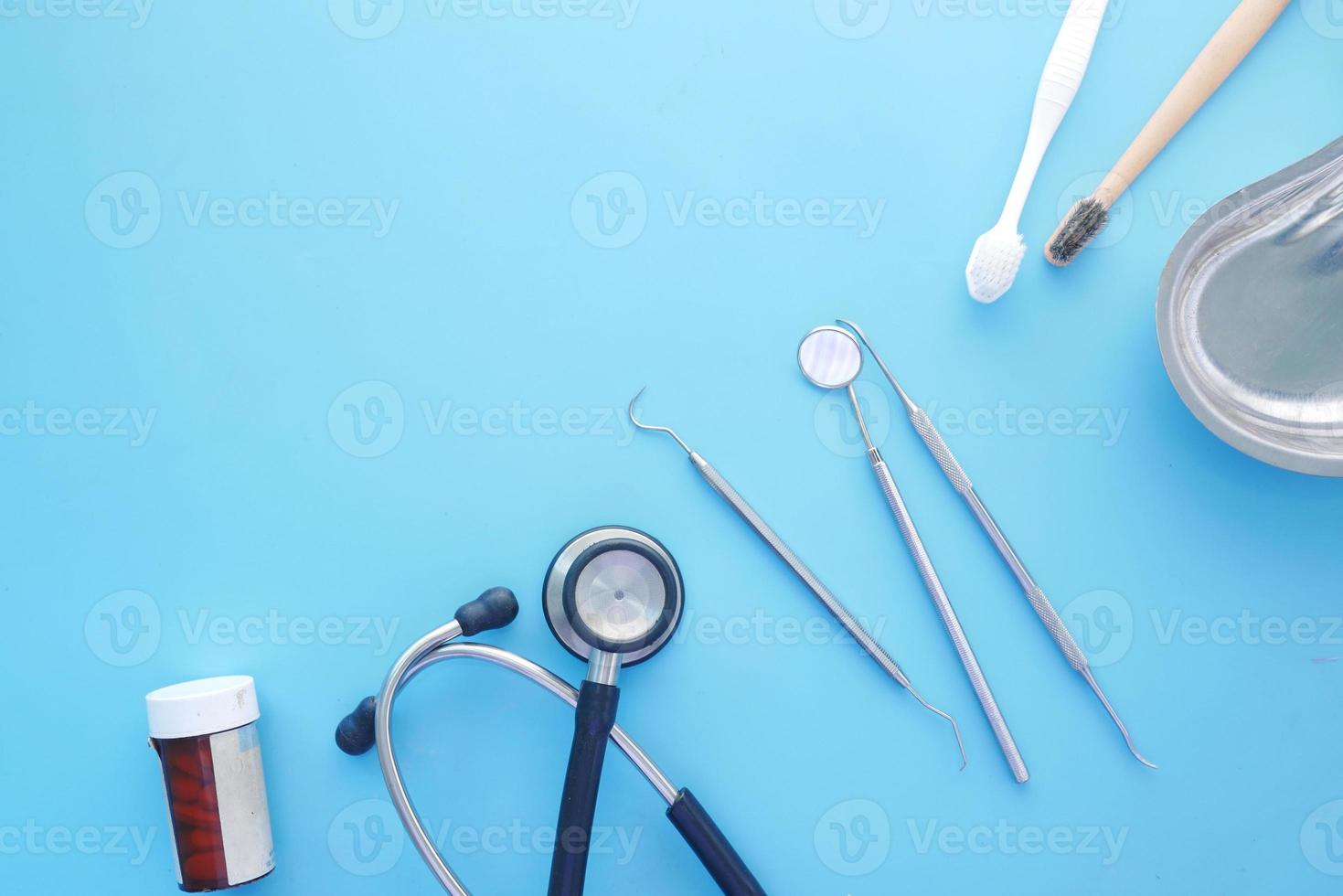 equipamento dentário, estetoscópio e pílula no fundo azul foto