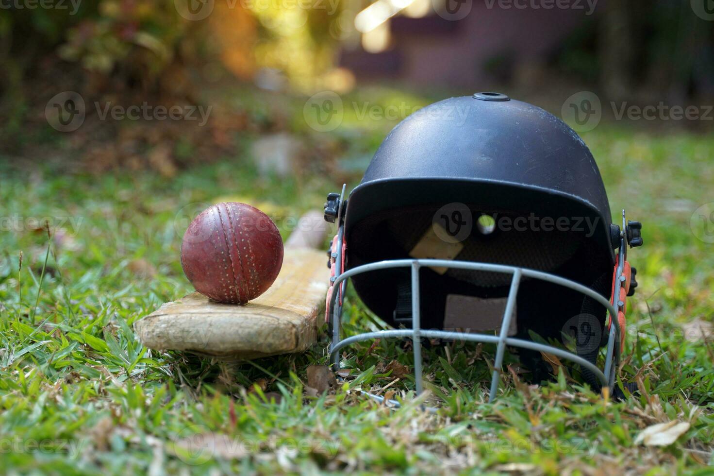 equipamento de críquete é uma bola de críquete, taco de críquete, capacete de críquete em um fundo de grama. foco suave e seletivo. foto