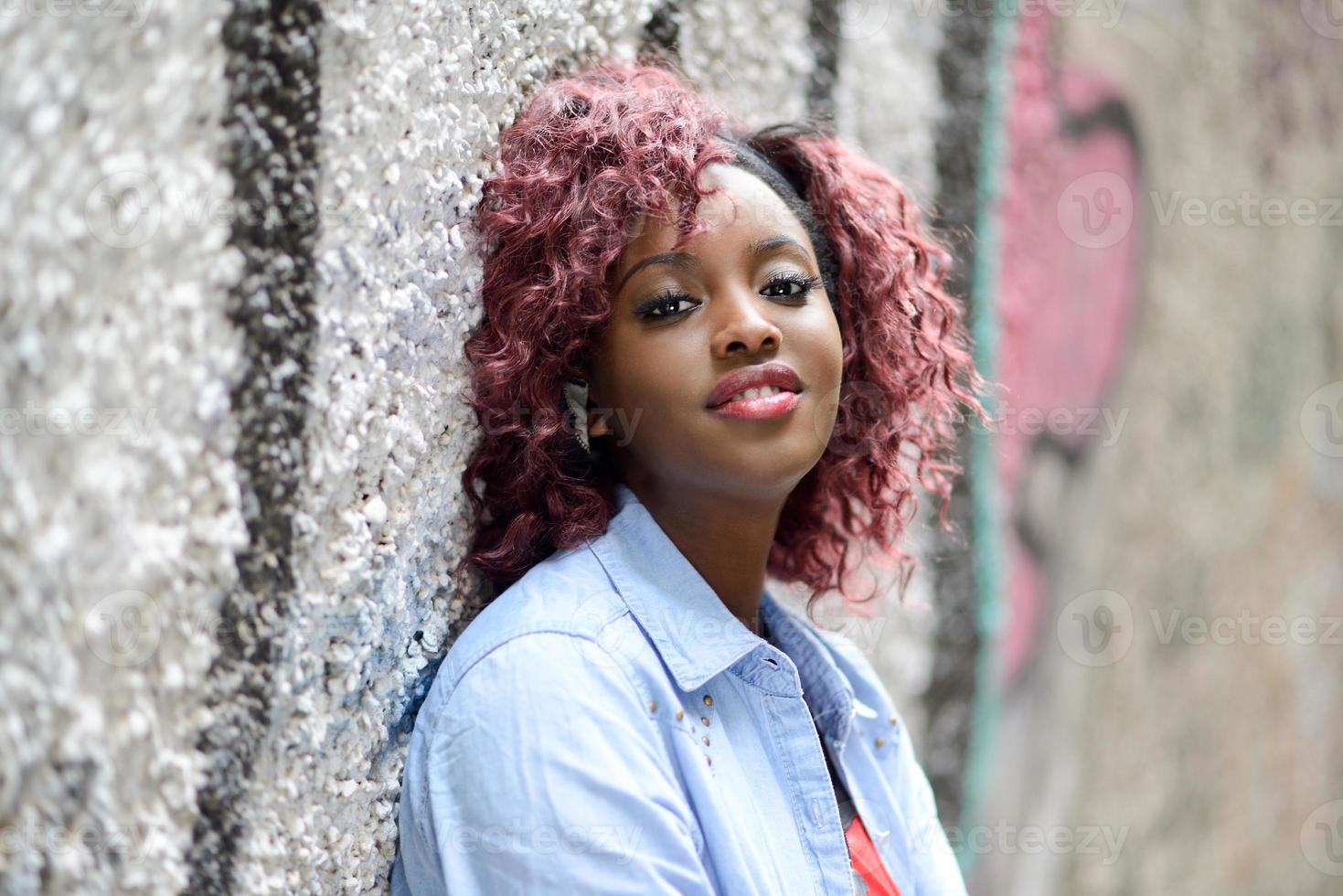 linda mulher negra em meio urbano com cabelo vermelho foto