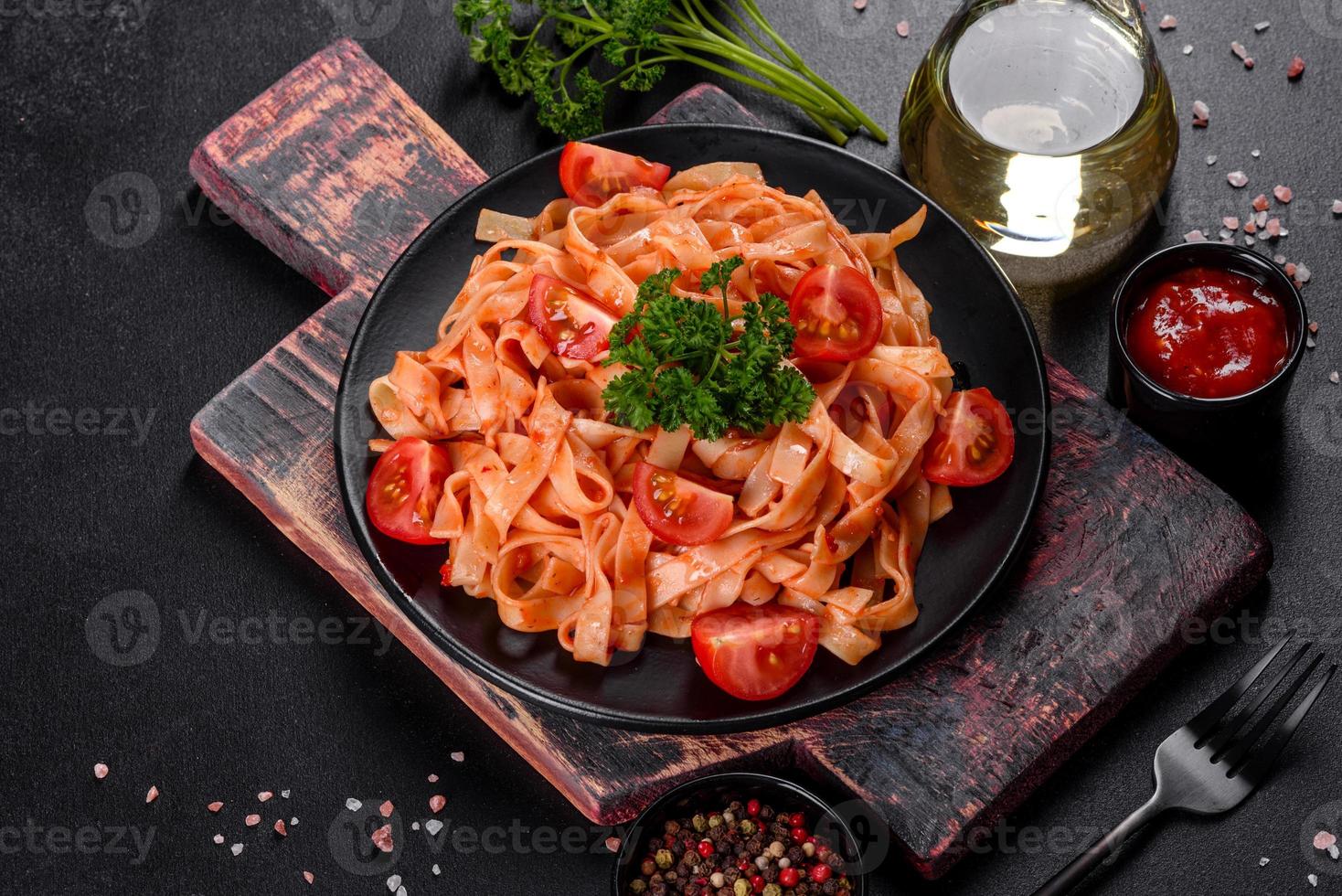 deliciosa pasta fresca com molho de tomate com especiarias e ervas em um fundo escuro foto