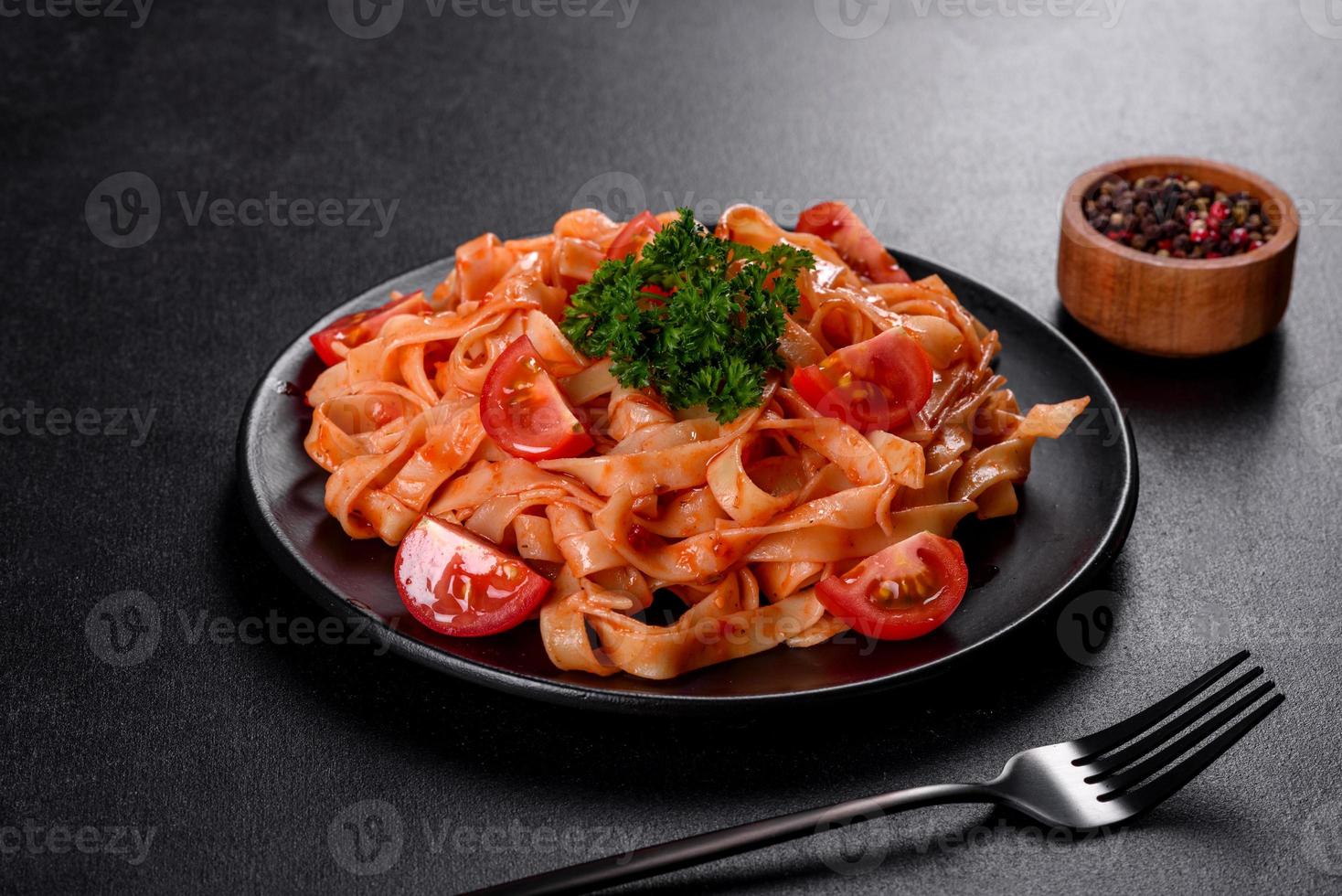 deliciosa pasta fresca com molho de tomate com especiarias e ervas em um fundo escuro foto