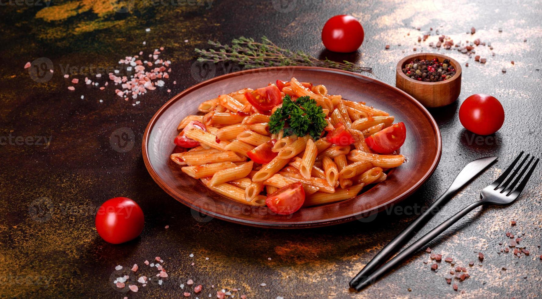 deliciosa pasta fresca com molho de tomate com especiarias e ervas em um fundo escuro foto