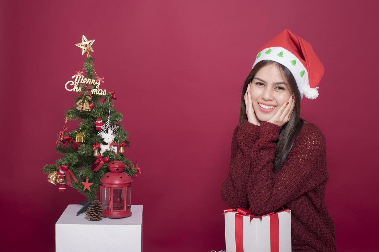 linda garota do papai noel em estúdio em fundo vermelho, conceito de natal foto