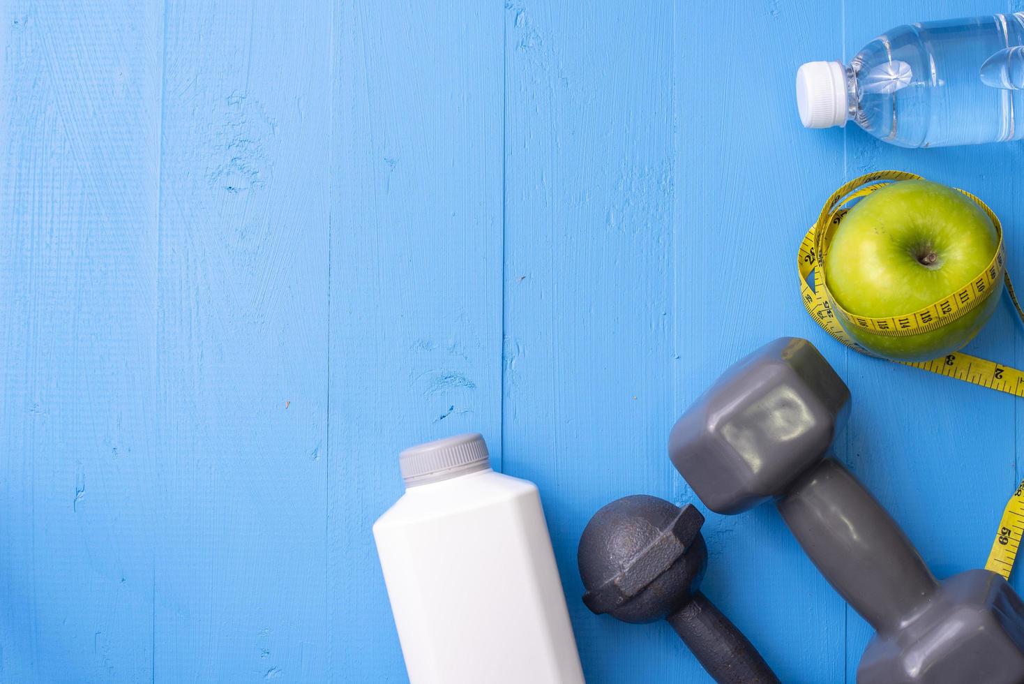 equipamentos de fitness e comida saudável em fundo azul de madeira foto